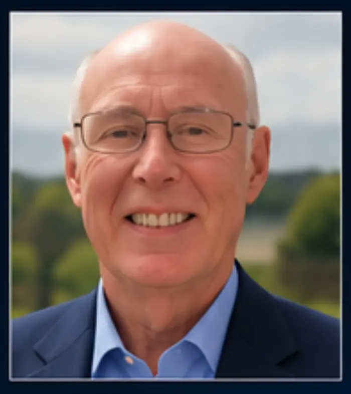R T Scanlon, author, smiling, wearing glasses and a navy jacket